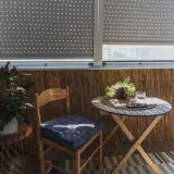 Przytulny balkon wnękowy z drewnianym krzesłem, stolikiem i roślinami. Idealne miejsce na poranną kawę.
