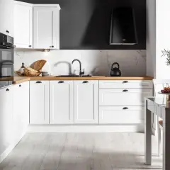 Biała kuchnia na wymiar z drewnianym blatem, czarnym okapem i marmurowym backsplash. Zastanawiasz się, ile kosztuje kuchnia na wymiar?