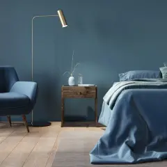 Przytulna sypialnia w odcieniach **kolor navy**. Miękki fotel, łóżko z pościelą i zasłony tworzą spokojną atmosferę.