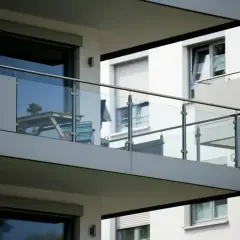 Nowoczesna loggia z przeszkloną balustradą, stolikiem i krzesłem, gotowa na poranną kawę.