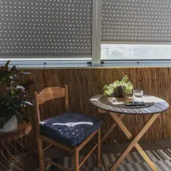Przytulny balkon wnękowy z drewnianym krzesłem, stolikiem i roślinami. Idealne miejsce na poranną kawę.