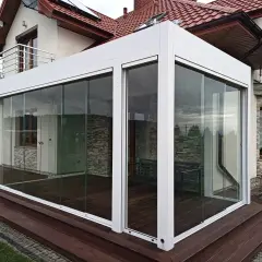 Nowoczesny taras zimowy z przeszklonymi ścianami i drzwiami, idealny do relaksu o każdej porze roku.
