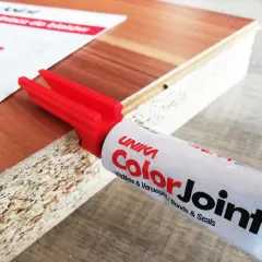 Klej do blatów ColorJoint i czerwony aplikator na krawędzi płyty meblowej.