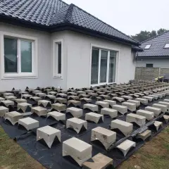 Budowa tarasu drewnianego na bloczkach betonowych. Podkład z agrowłókniny i betonowe podpory czekają na deski.