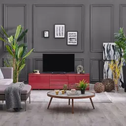 Nowoczesny salon z szarą ścianą w kolorze antracyt, która dodaje elegancji. Wygodna kanapa, czerwona szafka RTV i stolik kawowy tworzą przytulną przestrzeń.