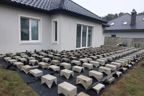 Budowa tarasu drewnianego na bloczkach betonowych. Podkład z agrowłókniny i betonowe podpory czekają na deski.