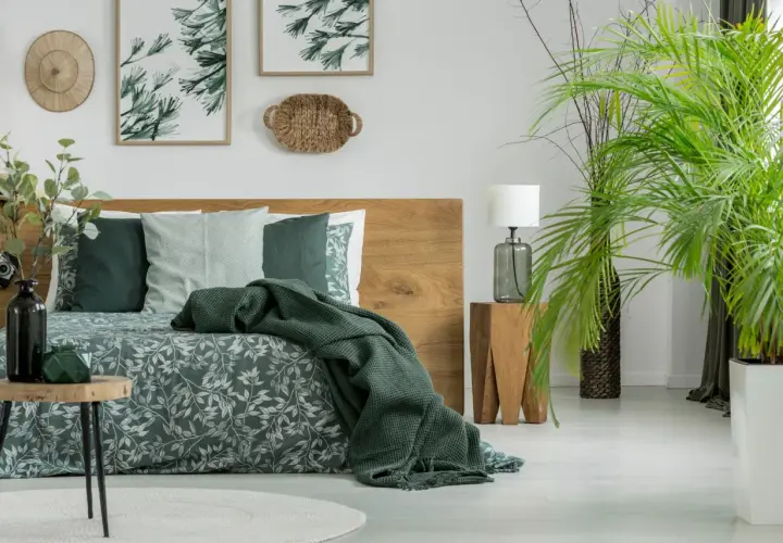 Sypialnia w stylu boho z drewnianym łóżkiem i pościelą w liście. Kolor khaki z czym łączyć? Z zielenią roślin i naturalnymi materiałami.