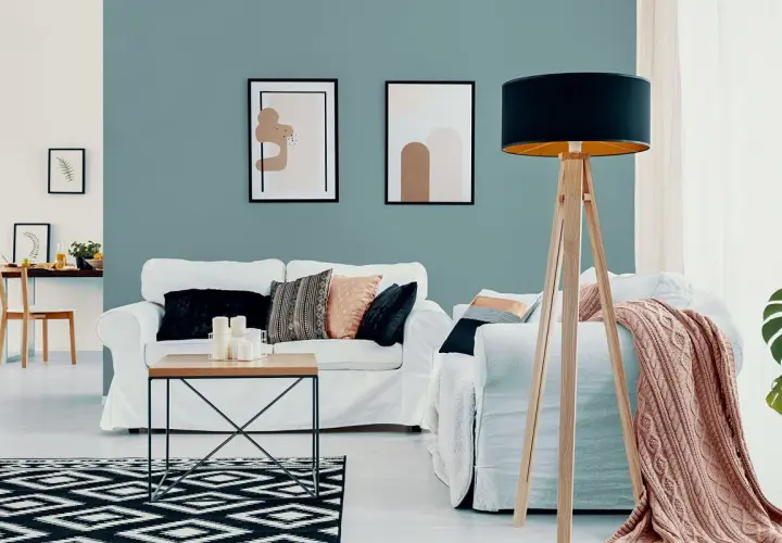 Nowoczesny salon z białymi sofami, stolikiem kawowym i dywanem w geometryczne wzory. Ściana w odcieniu **kolor lazurowy** tworzy spokojną atmosferę.