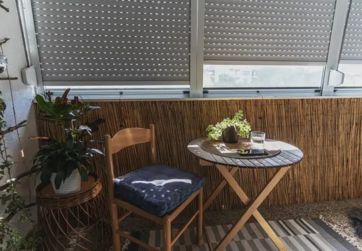Przytulny balkon wnękowy z drewnianym krzesłem, stolikiem i roślinami. Idealne miejsce na poranną kawę.