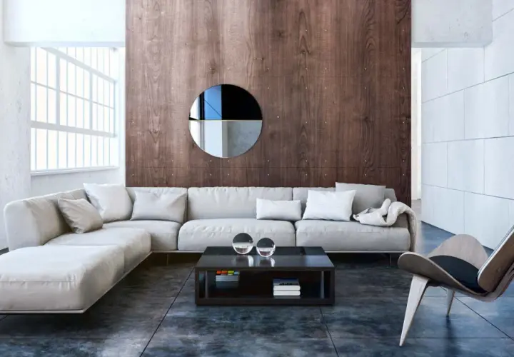 Nowoczesny salon w stylu bauhaus z wygodną, jasną sofą, drewnianą ścianą i designerskim fotelem.