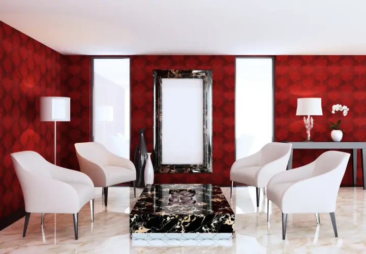 Elegancki salon z tapetą w kolorze rubinowym, cztery białe fotele, stolik kawowy z czarnego marmuru i ozdobne wazony.