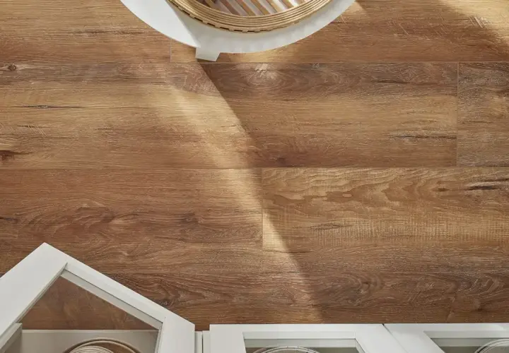 Drewnopodobne panele laminowane czy winylowe na podłodze, z widocznym fragmentem białej szafki i białego stolika.