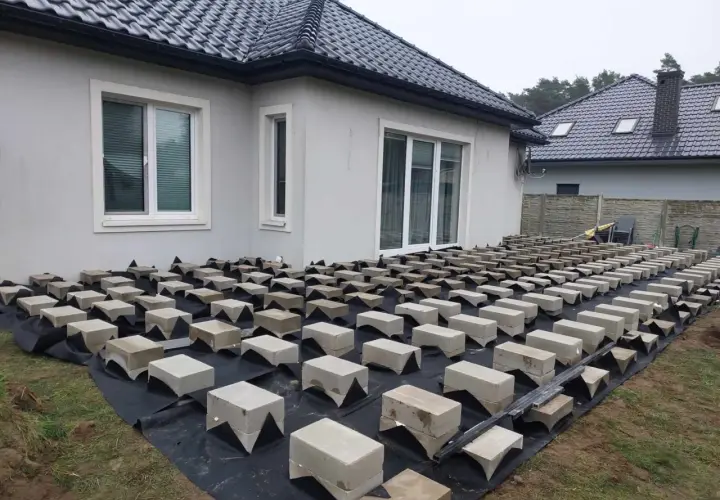 Budowa tarasu drewnianego na bloczkach betonowych. Podkład z agrowłókniny i betonowe podpory czekają na deski.