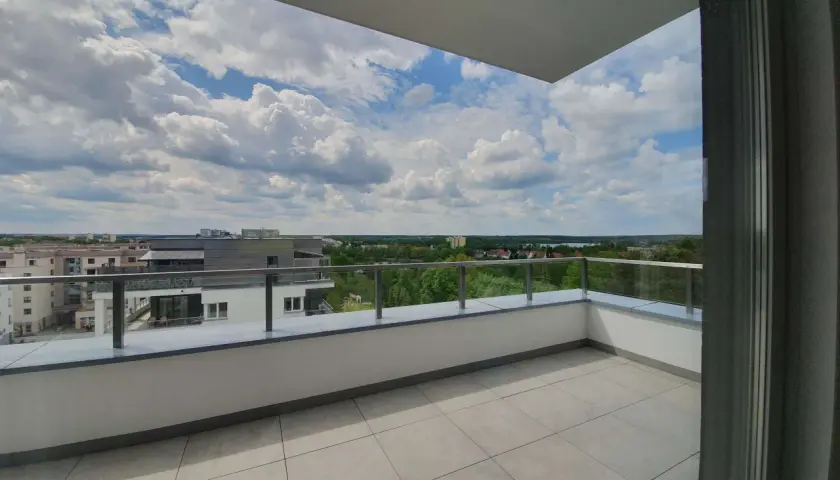 Przestronna loggia z widokiem na miasto i zieleń. Idealne miejsce na poranną kawę lub wieczorny relaks na balkonie.