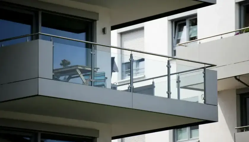 Nowoczesna loggia z przeszkloną balustradą, stolikiem i krzesłem, gotowa na poranną kawę.