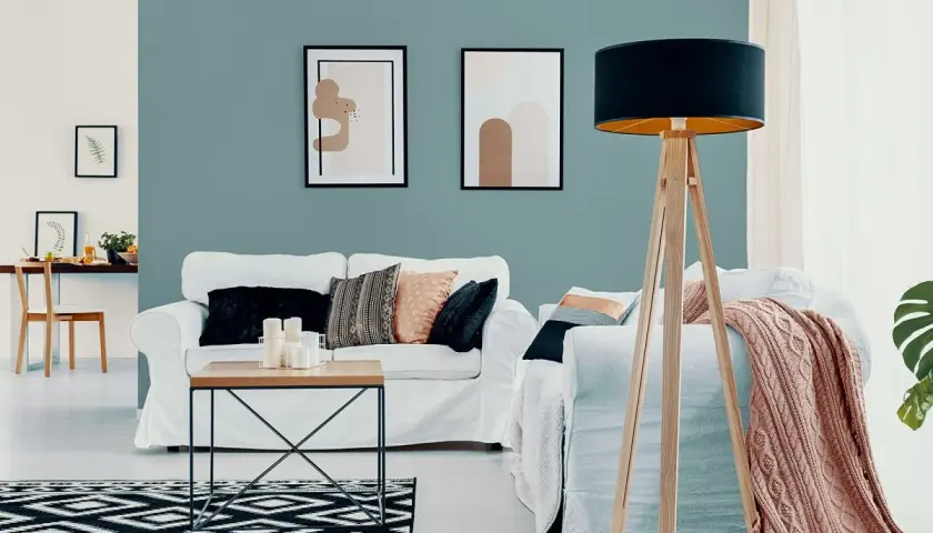 Nowoczesny salon z białymi sofami, stolikiem kawowym i dywanem w geometryczne wzory. Ściana w odcieniu **kolor lazurowy** tworzy spokojną atmosferę.