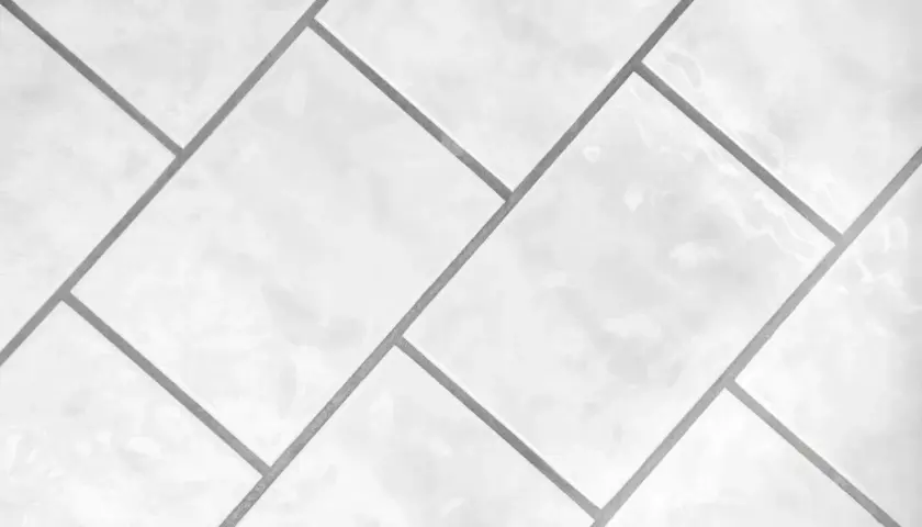 Białe, błyszczące płytki ułożone w geometryczny wzór. Precyzyjna rektyfikacja płytek zapewnia idealnie równe fugi.