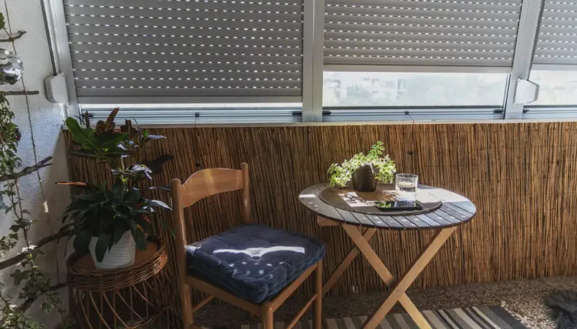 Przytulny balkon wnękowy z drewnianym krzesłem, stolikiem i roślinami. Idealne miejsce na poranną kawę.
