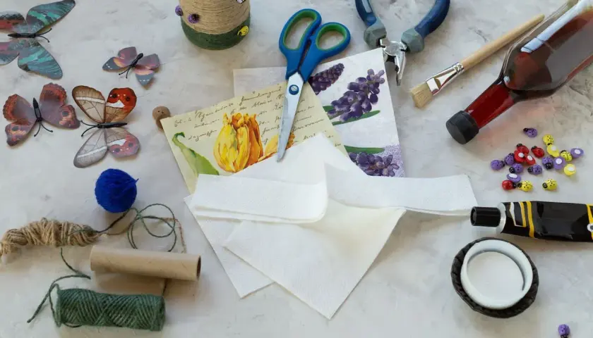 Materiały do decoupage: serwetki z motywami, nożyczki, klej, pędzel, butelka, sznurki, ozdobne biedronki.