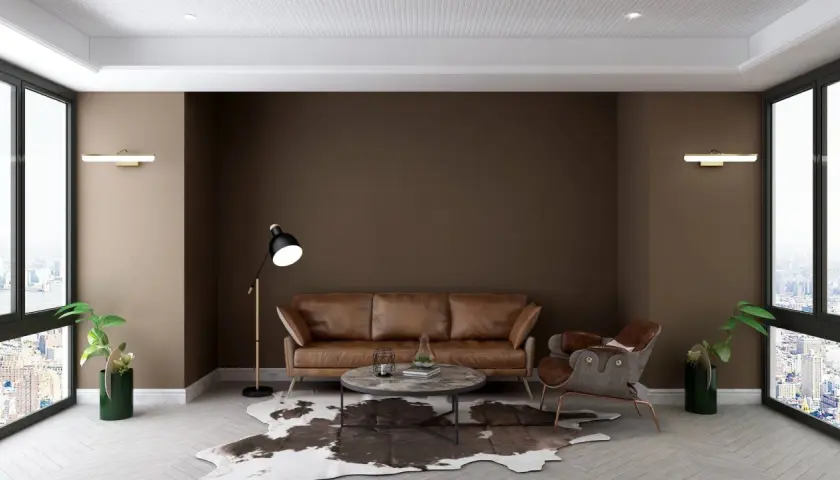 Elegancki salon z kanapą w kolorze **brunatnym**, marmurowym stolikiem i fotelem. Duże okna wychodzą na miasto.