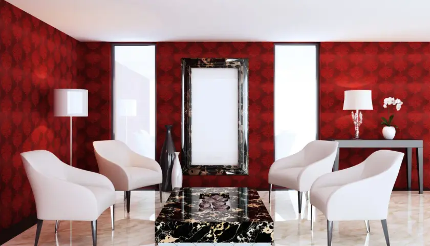 Elegancki salon z tapetą w kolorze rubinowym, cztery białe fotele, stolik kawowy z czarnego marmuru i ozdobne wazony.