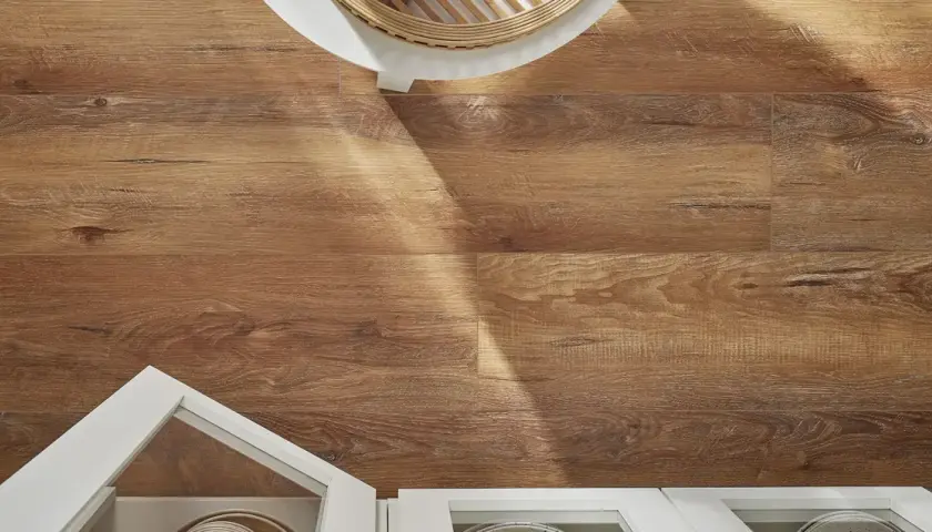Drewnopodobne panele laminowane czy winylowe na podłodze, z widocznym fragmentem białej szafki i białego stolika.