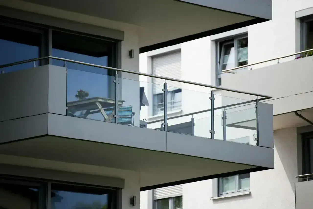 Nowoczesna loggia z przeszkloną balustradą, stolikiem i krzesłem, gotowa na poranną kawę.
