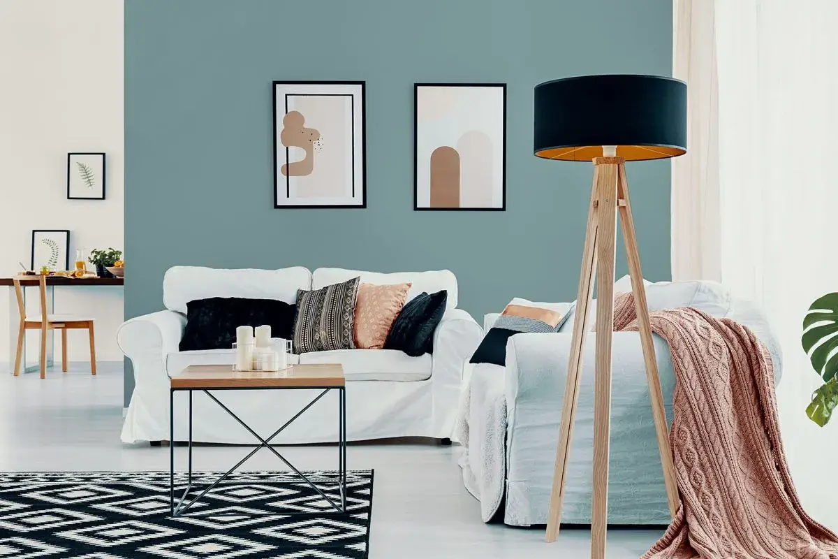 Nowoczesny salon z białymi sofami, stolikiem kawowym i dywanem w geometryczne wzory. Ściana w odcieniu **kolor lazurowy** tworzy spokojną atmosferę.