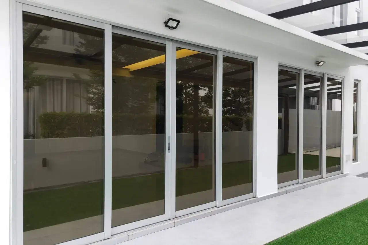 Nowoczesne drzwi tarasowe ze szkłem dymionym, odbijające zieleń ogrodu i architekturę domu.