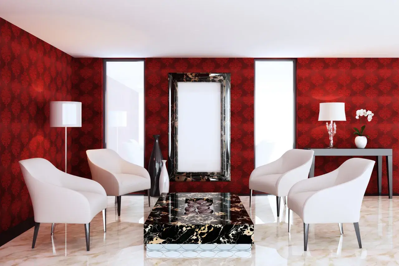 Elegancki salon z tapetą w kolorze rubinowym, cztery białe fotele, stolik kawowy z czarnego marmuru i ozdobne wazony.