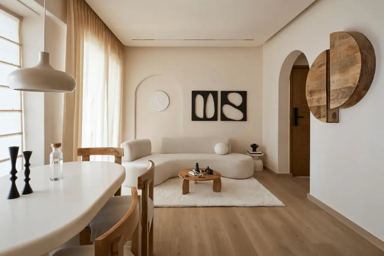 Nowoczesny salon z sofą o organicznym kształcie, drewnianym stolikiem i dywanem. Minimalizm w domu podkreślają geometryczne obrazy i dekoracje.